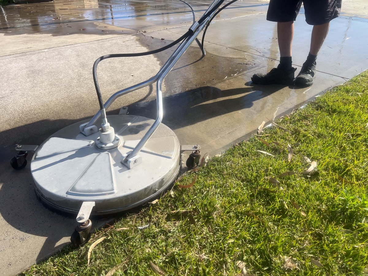 Worker using a floor and surface pressure washer cleaner high-pressure water spray to remove loose paint, mold, grime, dust, mud, and dirt from surfaces