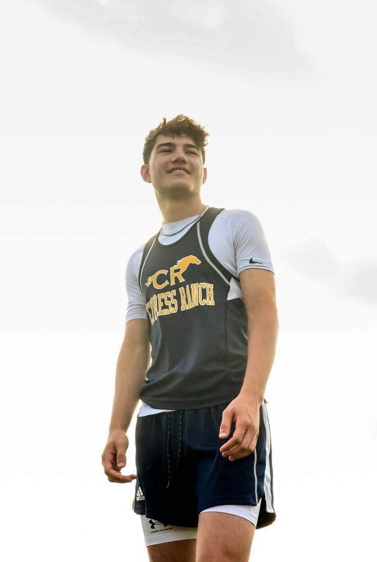 Young male athlete in Cross Country running uniform standing against overcast sky