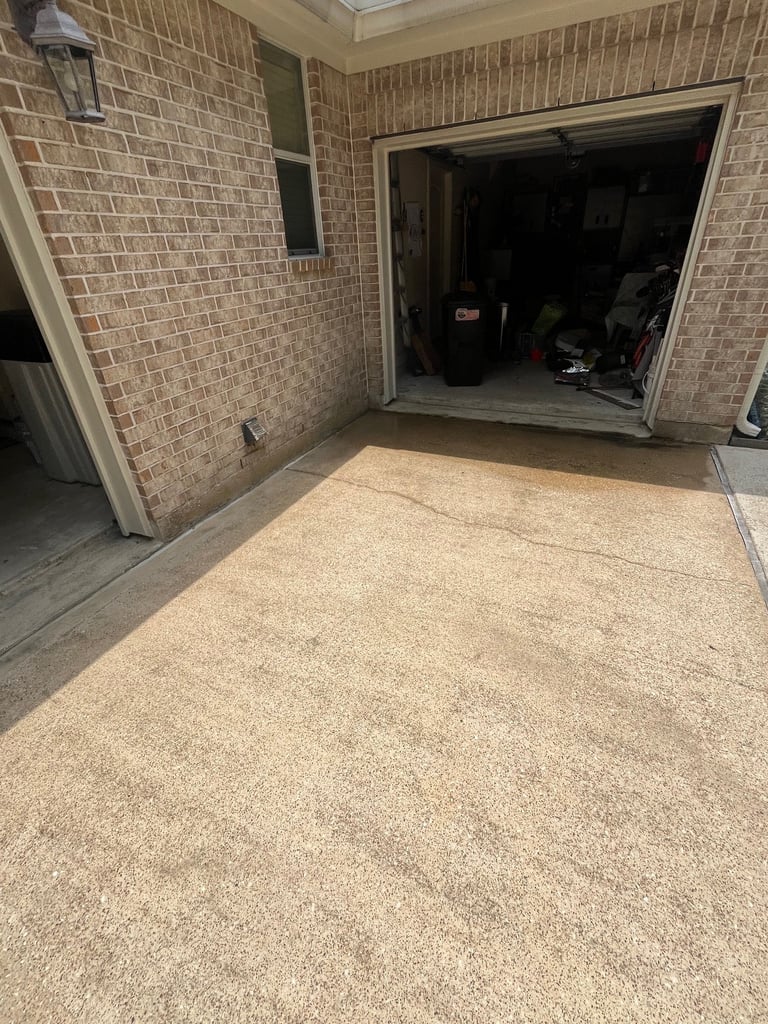 Empty garage interior with brick walls, concrete floor, and open garage door leading to dark interior space